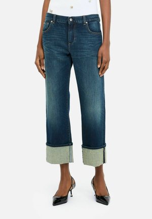 Blugi cropped din denim bleu închis, cu un tiv răsfrânt într-o nuanță mai deschisă. Prezintă un stil clasic cu cinci buzunare și închidere cu nasture.