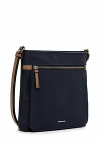 Námorně modrá crossbody taška vyrobená z látky s hladkým povrchem, s přední kapsou na zip a koženými detaily. Nastavitelný ramenní popruh.