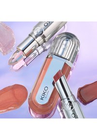 Två KIKO Milano läppstift och ett läppglans i nude- och rosa nyanser med färgfläckar på en reflekterande lavendelfärgad yta.