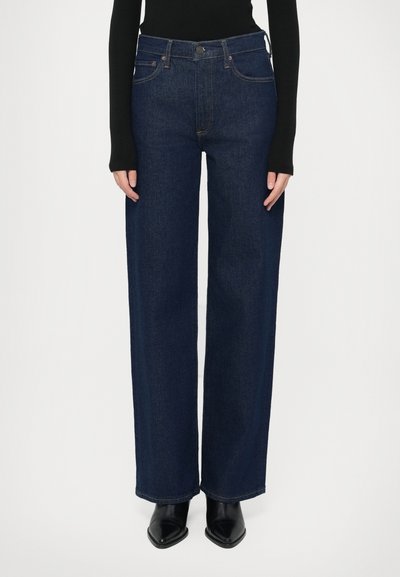 Jean en denim sombre à jambes larges avec une taille haute, doté d'une fermeture à boutons, d'un design classique à quatre poches et de détails de couture subtils.