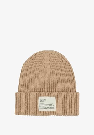 Beige ribbed knit beanie with folded cuff featuring a fabric label defining "thank-ful" and listing synonyms and its meaning.