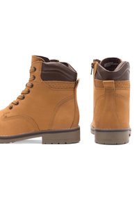 Brūni ādas potītes zābaki ar noapaļotu purngalu, metalizētām acs caurumiem, mīksto apkakli un sānu rāvējslēdzēju. Strukturēti akcenti un izturīga gumijas zole.