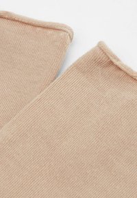 Beige stickad tyg med fin textur och en slät finish, med råa kanter och lätt varierande vävstruktur.