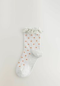 Helle graue Socken mit orangen Punkten, ausgestattet mit einem Rüschensaum aus leicht grünlich-grauem Material. Weicher Textil über die gesamte Socke.