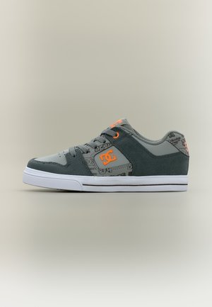 Grå og sort skate-sko med orange DC-logo, mønstret sidepanel, sorte snørebånd og hvid sål på neutral baggrund.