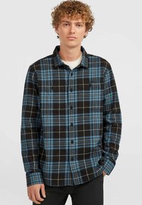Camisa de cuadros en azul y negro, con cuello, cuenta con un bolsillo en el pecho y botones negros, hecha de una tela suave y texturizada.