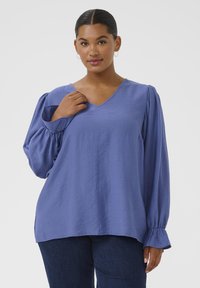 Blue V-neck blouse with puffed long sleeves and ruffled cuffs, made from a lightweight fabric, featuring a relaxed fit and smooth texture.
