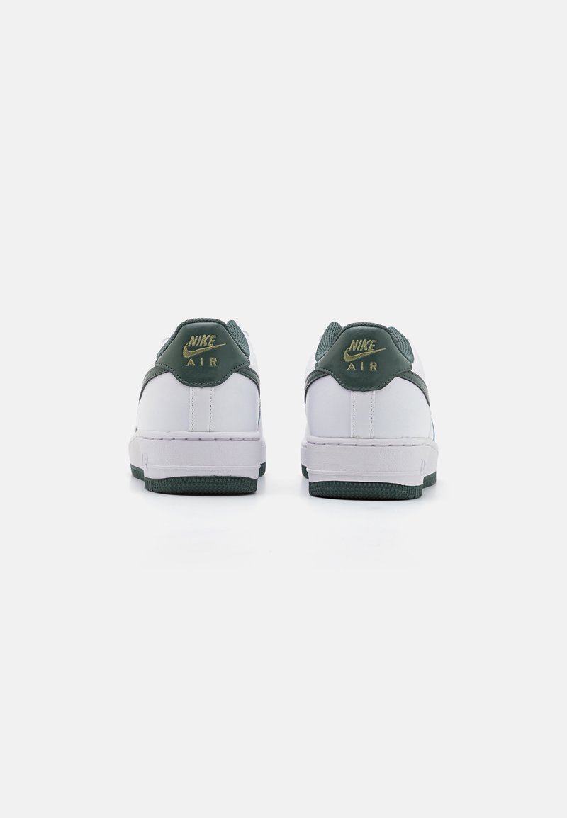 Le sneakers Nike Air presentano un corpo in pelle bianca con accenti verdi. Il retro ha un marchio dorato e una suola in gomma verde testurizzata.