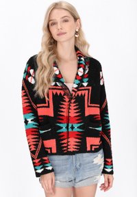 Zwarte cardigan met kleurrijke geometrische patronen in rood, turquoise en wit. Voorzien van een sjaalkraag en een zachte, gestructureerde stof.