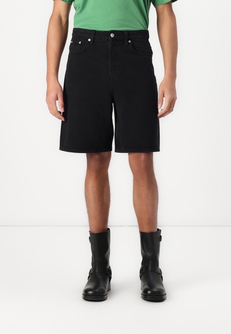 Sorte denimshorts med en lige pasform, femlomme-design og kontrastsyninger, parret med sorte læder ankelstøvler.