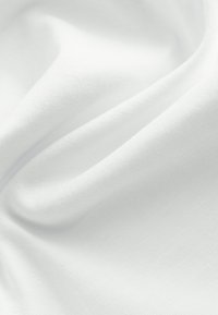 Tissu blanc lisse avec des plis doux et une texture subtile visible en gros plan.