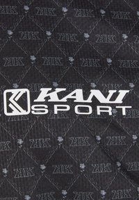 Juodas audinys su deimanto raštu, mažais logotipais ir tekstu "KANI SPORT" storomis baltomis raidėmis. Textūruotas ir sportiškas dizainas.