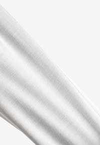 Tessuto bianco con una superficie fine e texturizzata, che mostra modelli di intreccio dettagliati. Il tessuto è liscio e si allunga leggermente.