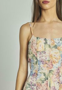 Robe florale aux couleurs pastel, dotée de fines bretelles et d'un corsage ajusté. Fabriquée en tissu léger avec une finition texturée.