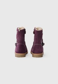 Paarse suède enkellaarsjes met faux fur voering, decoratieve stiksels en een zijgesp. Heeft een platte, gestructureerde rubberen zool.