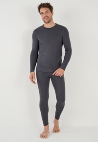 Camiseta térmica de manga larga gris y pantalones ajustados a juego, hechos de una tela suave con una textura lisa. Presenta un cuello redondo y puños elásticos.
