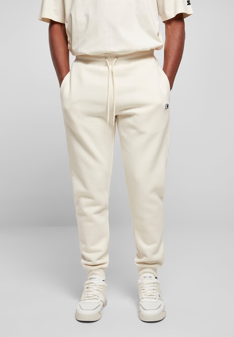 Cremefarvede sweatpants lavet af blødt stof, med snørretalje, sidelommer og et lille logo-detalje på benet.