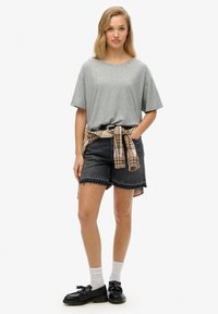 Grå bomulds t-shirt, sorte denim shorts med frynset kant, ternet skjorte knyttet om taljen, sorte sko og hvide sokker.