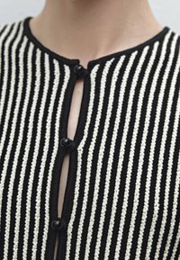 Svart- och vitrandig stickad kofta med rund halsringning, som har knappstängning och en texturerad tygdesign.