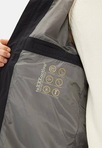 Zwarte buitenjas met een interieur van een grijs gerecycled membraan, voorzien van iconen voor waterdichte, ademende en winddichte kwaliteiten.