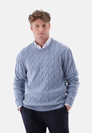 Light blue cable-knit sweater made of soft material, featuring a round neckline and ribbed cuffs, worn over a white collared shirt.