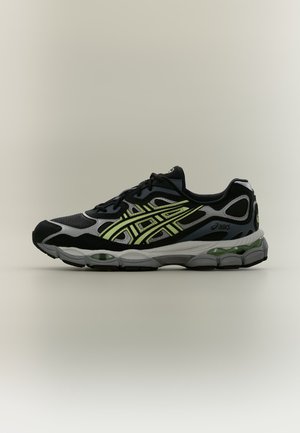 Chaussure de running noire et grise avec des accents jaunes et une semelle amortie, vue latérale sur fond clair uni.