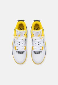 Paire de chaussures de sport blanches avec des accents jaunes et des détails en mesh, vues de dessus sur un fond gris clair.