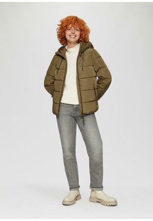 Olijfgroene pufferjas met capuchon, ritszakken, crèmekleurige trui, grijze spijkerbroek en beige enkellaarzen. Gladde textuur, casual ontwerp.