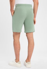 Grüne Baumwollshorts mit einem elastischen Bund, seitlichen Taschen und einer Gesäßtasche. Das Design ist lässig und sitzt oberhalb des Knies.