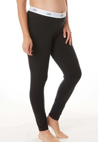 Zwarte leggings van rekbaar materiaal, met een witte elastische tailleband met bedrukte branding. Gladde textuur, strakke pasvorm.