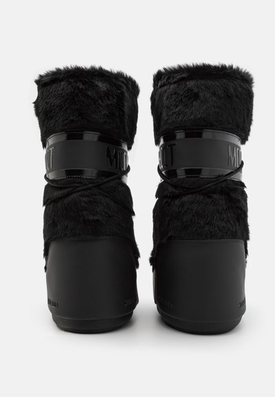 Bottes en fausse fourrure noire avec des bords noirs brillants, hauteur mi-mollet, bout rond et semelles en caoutchouc texturé. Présente un logo sur la sangle.