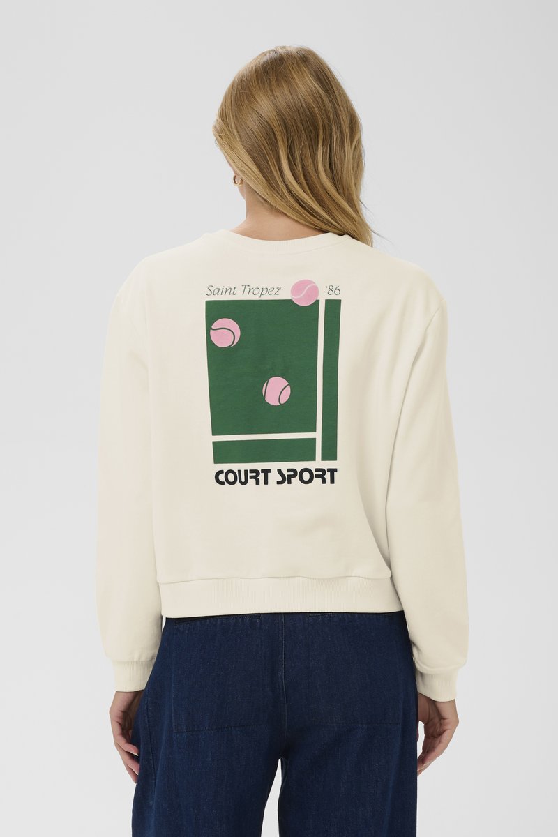 Felpa color crema con taglio corto, decorata con una grafica verde di palline da tennis, la scritta "Saint Tropez '86" e "COURT SPORT".