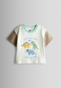 Biała i beżowa koszulka z krótkim rękawem dla malucha z niebieskimi, zielonymi i żółtymi ilustracjami dinozaurów oraz napisem "Dino Bedtime Club Snoozesaurus".