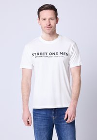 Biała bawełniana koszulka z czarnym napisem „STREET ONE MEN ORIGINAL SUPPLY CO. WORN WITH PURPOSE.” Krótkie rękawy, okrągły dekolt.