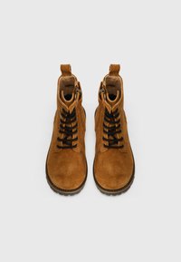 Bruna mocka ankle boots med svarta snören, sidodragkedjor och dragflikar. Har en texturerad yta och robusta gummisulor.
