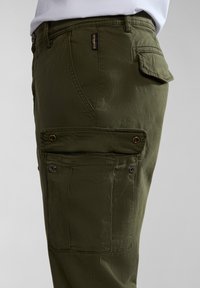 Cargo-Hosen aus einem olivgrünen Baumwollmix, mit Seitentaschen, Druckknopfverschluss und einer glatten Textur mit dezenten Nähdetails.