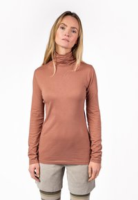 Langärmliges Rollkragenshirt in gedämpftem Terrakotta, glatte Textur, taillierte Passform, kombiniert mit hellgrauen gerippten Shorts.