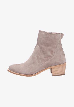 Bottines en cuir suédé taupe avec un bout arrondi et un talon empilé moyen. Texture lisse, design minimaliste et subtil détail de découpe sur le côté.