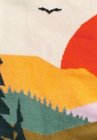 Strickstoff mit einem Landschaftsdesign, das eine große orangefarbene Sonne, gelbe Hügel, grüne Bäume und die Silhouette eines schwarzen Vogels darüber zeigt.