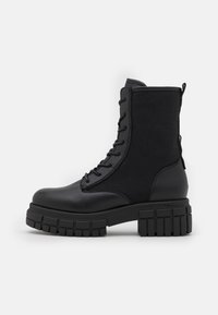 Black combat boot with thick lug sole, lace-up front, and fabric and leather upper, photographed on a white background.