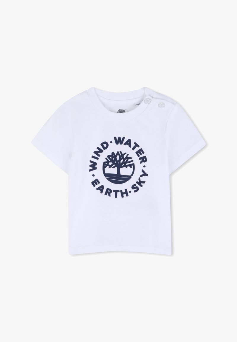 T-shirt en coton blanc avec un imprimé bleu marine comprenant le texte "VENT • EAU • TERRE • CIEL" et un graphisme d'arbre, manches courtes et détail de boutons-pression.