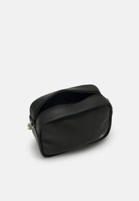 Black leather bag with a rectangular shape, featuring a zippered top and a silver accent. Smooth texture, minimalist design.