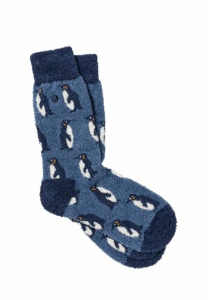 Par de calcetines azules y peludos con puños, talones y dedos de color azul oscuro, con un patrón repetitivo de pequeños pingüinos.