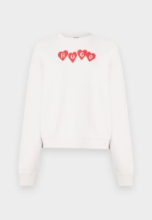 Weißes Sweatshirt mit einem kurzen Schnitt, verziert mit roten Herzformen und dem Schriftzug "HUGO" in roter Schrift über der Brust.