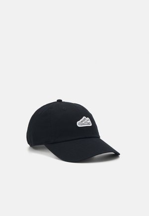 Schwarze Baumwollmütze mit gebogenem Schirm und einem weißen Sneaker-Patch auf der Vorderseite. Verstellbarer Riemen auf der Rückseite für einen sicheren Sitz.