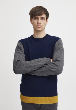 Navy and gray sweater with a yellow hem, made of knit material. Crew neck design with contrasting color blocks on sleeves.