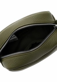 Alyvuogių žalios odos krepšys su tekstūruota paviršiaus danga, turi sidabrinį užtrauktuką ir atvirą viršų, matomas tamsus vidus bei mažytė kišenėlė.