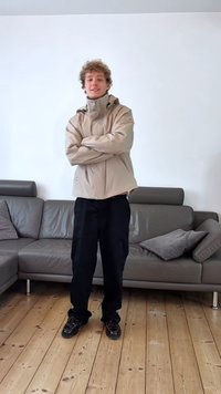 Light beige jacket with a high collar, black pants, and dark shoes. The texture is smooth, with a relaxed fit and a simple design.