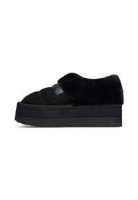 Scarpe slip-on nere con zeppa, realizzate con un upper in pelliccia morbida e una base in suede testurizzata. Presentano un patch con logo e una suola in gomma spessa.