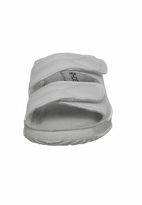 White sandal featuring a soft leather upper with two adjustable Velcro straps. The sole is textured for grip and has a slight curvature.